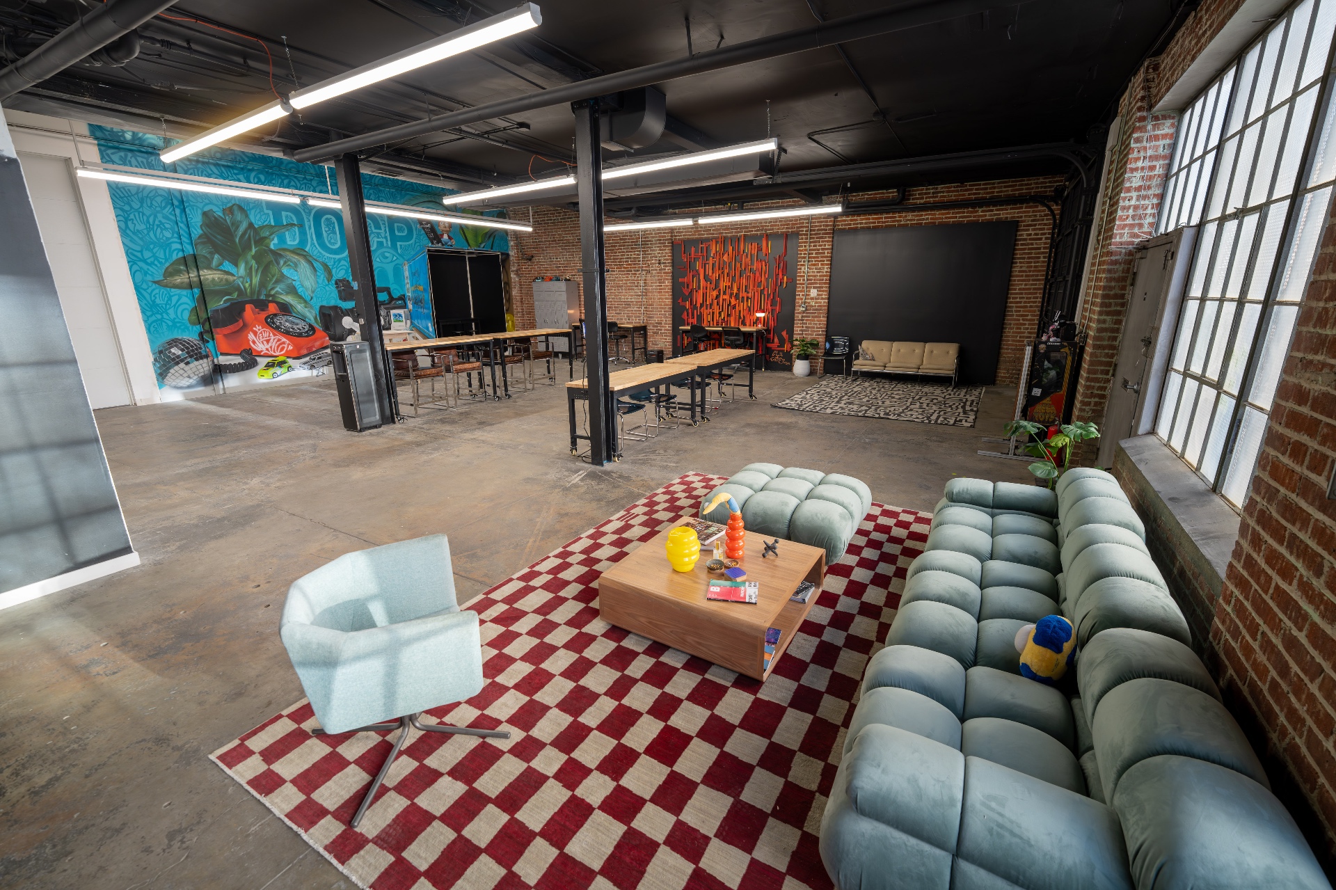 Co-creating floor — brass-lit communal table, exposed brick
